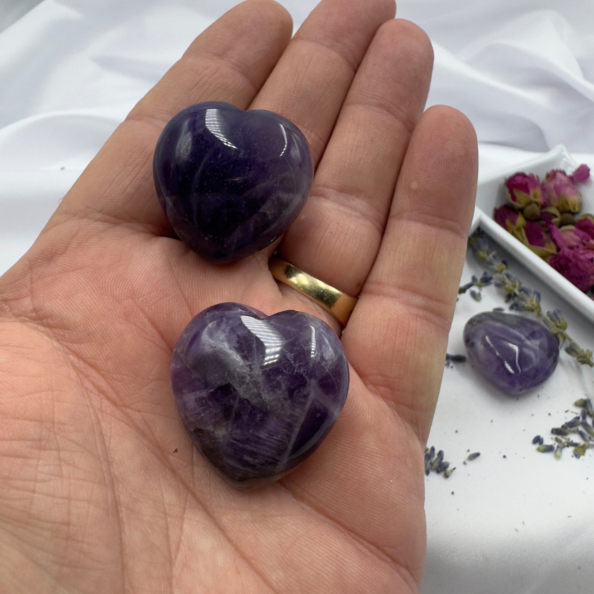 Hand holding polished chevron amethyst heart crystals with purple and white banded patterns
