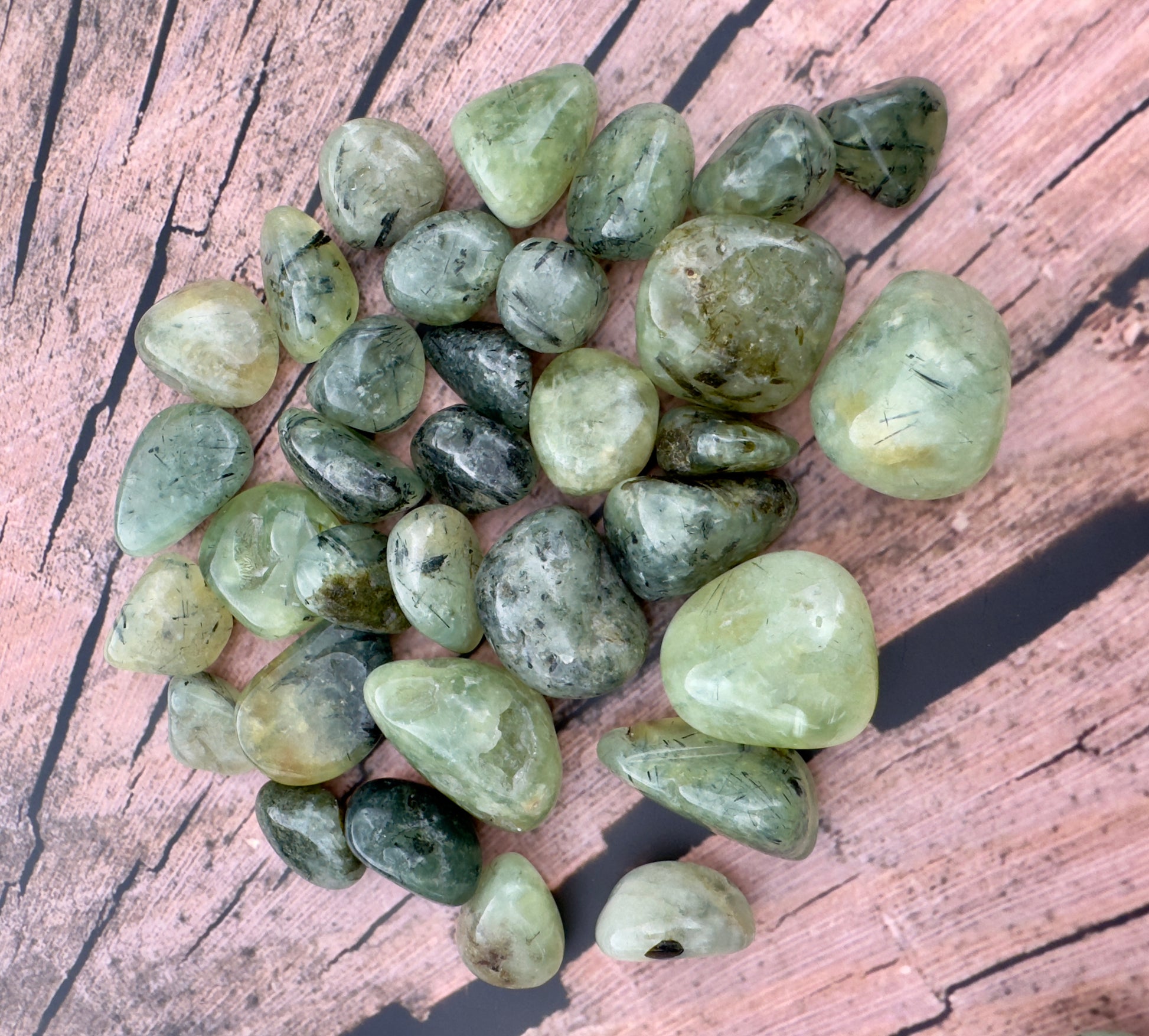 Davinas green prehnite tumbled stone collection with smooth polished surfaces on wooden background