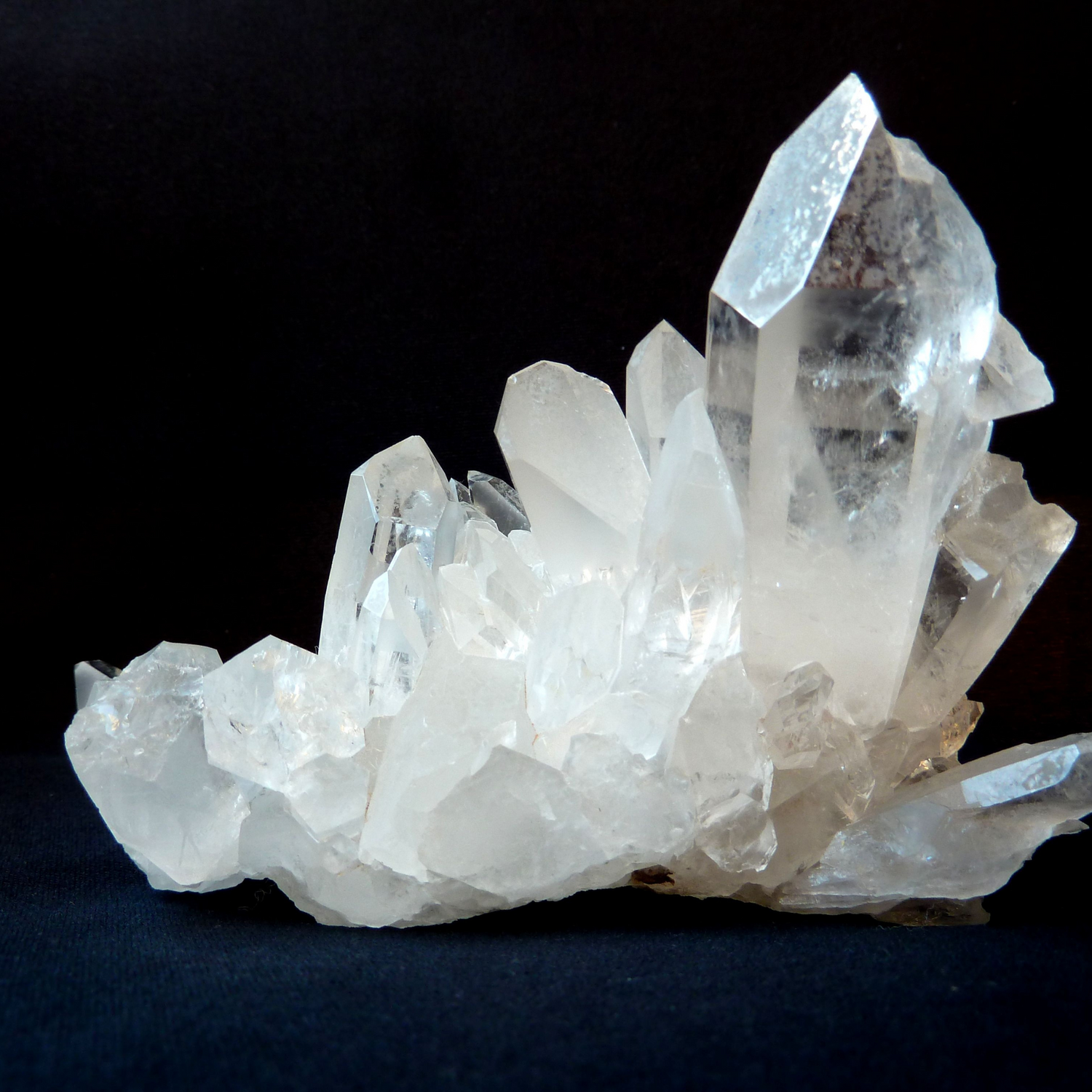Cluster of clear quartz crystals with sharp points and translucent clarity on black background