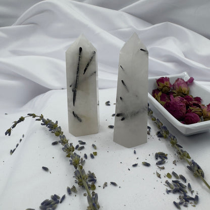 Davinas black tourmaline tower standing on white fabric with dried lavender and rose petals nearby