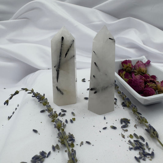 Davinas black tourmaline tower standing on white fabric with dried lavender and rose petals nearby