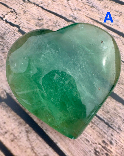 Davinas green fluorite crystal heart with smooth polished surface on textured background