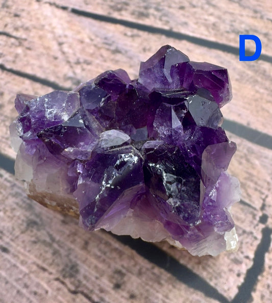 Davinas amethyst raw crystal cluster with deep purple points on a light rock base